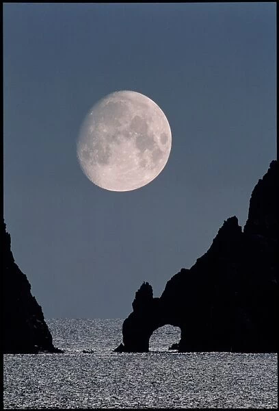 Gibbous moon rising over a coastal cliff