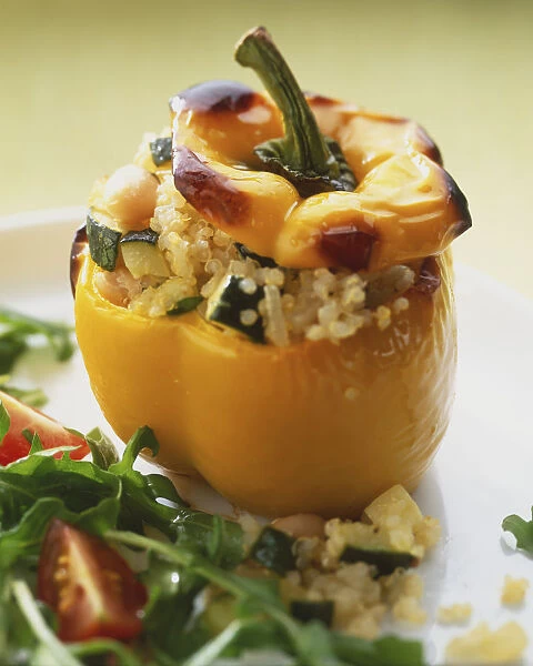 Yellow pepper, stuffed with mixture of courgettes and grains, salad garnish in front