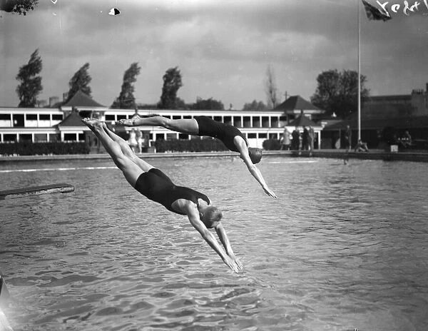 Diving. 1929: A man and a woman diving into a pool from a diving board