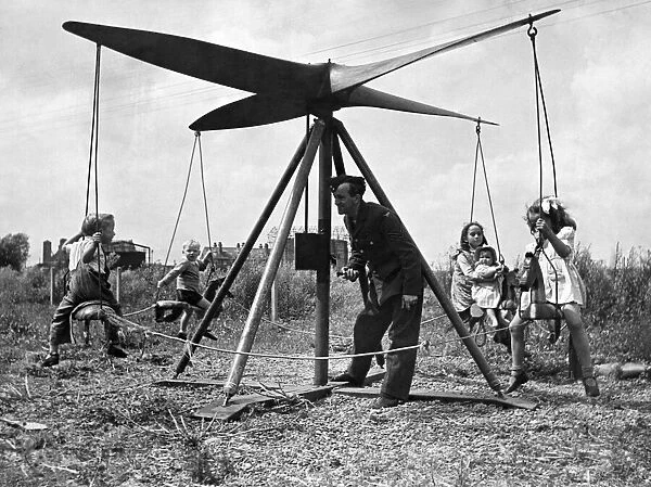 A airman operates a propeller roundabout. Seen here giving local children a ride