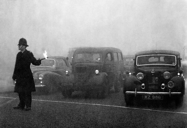 Policeman on point duty seen here using flares to guide the traffic during a heavy smog