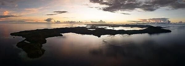 Sunrise illuminates clouds that drift over the calm waters of the Solomon Islands. This scenic region is known for its high marine biodiversity
