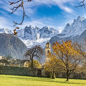 Old church lit by autumn colors with snowcapped Piz Badile and Cengalo in the background, Soglio, Graubunden, Switzerland, Europe