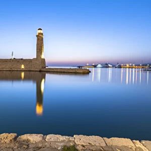 Old lighthouse reflected in the calm sea during the blue hour, Rethymno, Crete island, Greek Islands, Greece, Europe