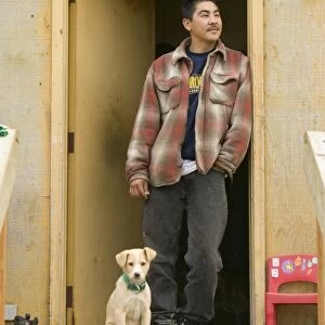 An Inuit man and puppy on Shishmaref a tiny island between alaska and siberia in the Chukchi sea is home to around 600 inuits or eskimos. As hunter gatherers their carbon footprint is tiny and as such are least responsible for global warming. Yet