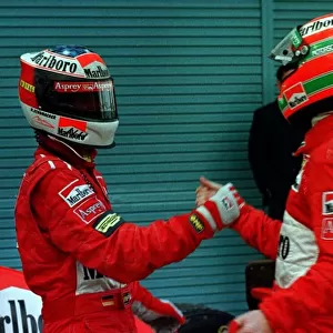 1997 JAPANESE GP. Michael Schumacher celebrates with team mate Eddie Irvine after they both finish on the podium, 1st and 3rd respectively. Photo: LAT