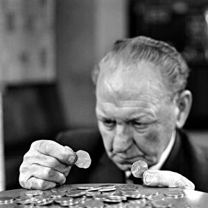 Elderly man studying a new fifty pence close up. November 1969 Z11025-004