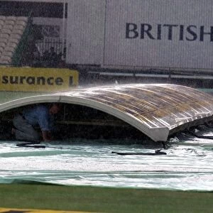 Groundsman Peter Marron Shelters From The Rain Under The Covers At Old Trafford
