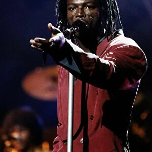 Seal singer on stage sings into microphone with dreadlocks