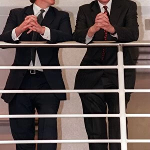Tony Blair looks sideways at Donald Dewar April 1999 leaning on railings at the new